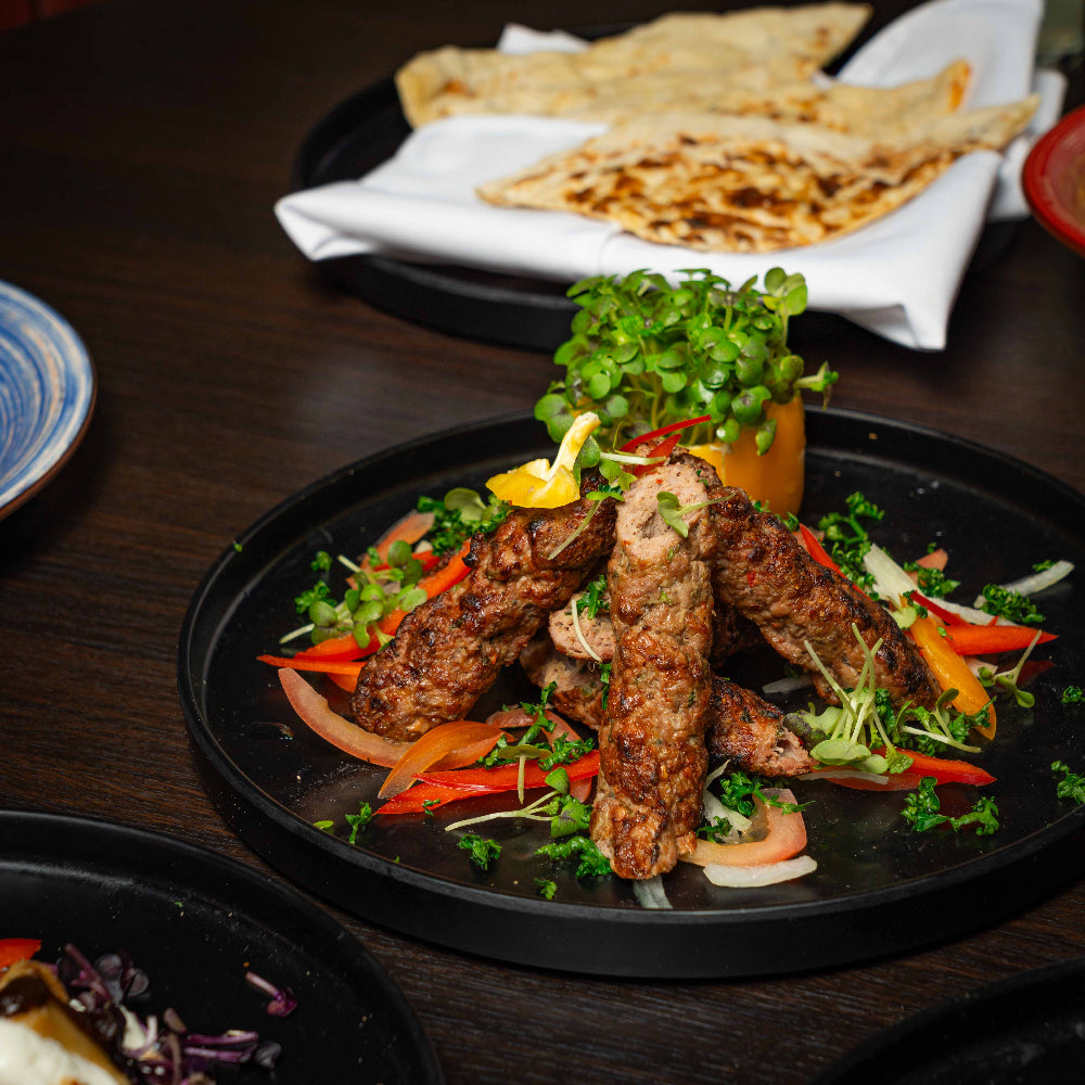 Plated dish of grilled meat with vegetables on a dark surface