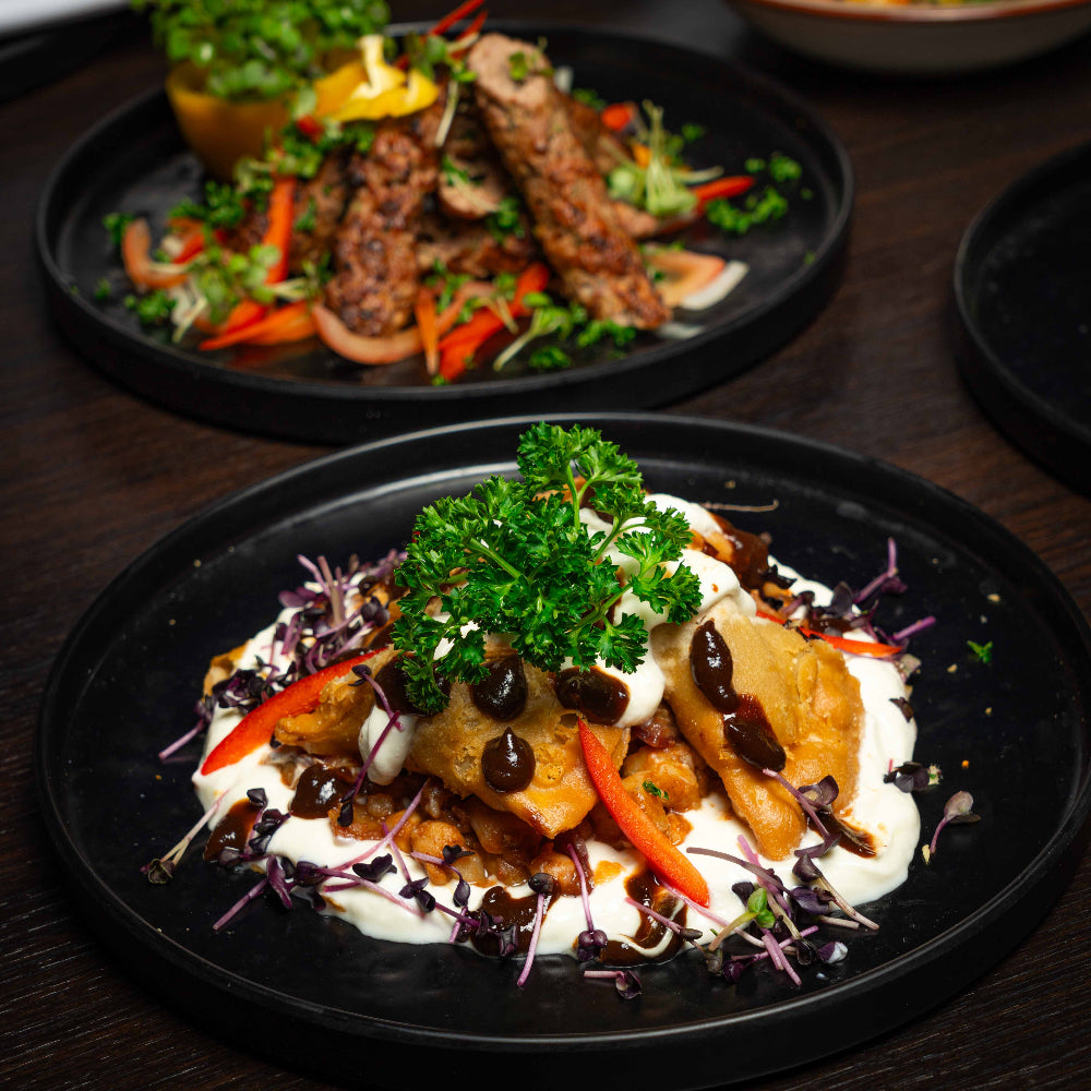 Plated dish somosa chatt with meat and vegetables on a dark surface