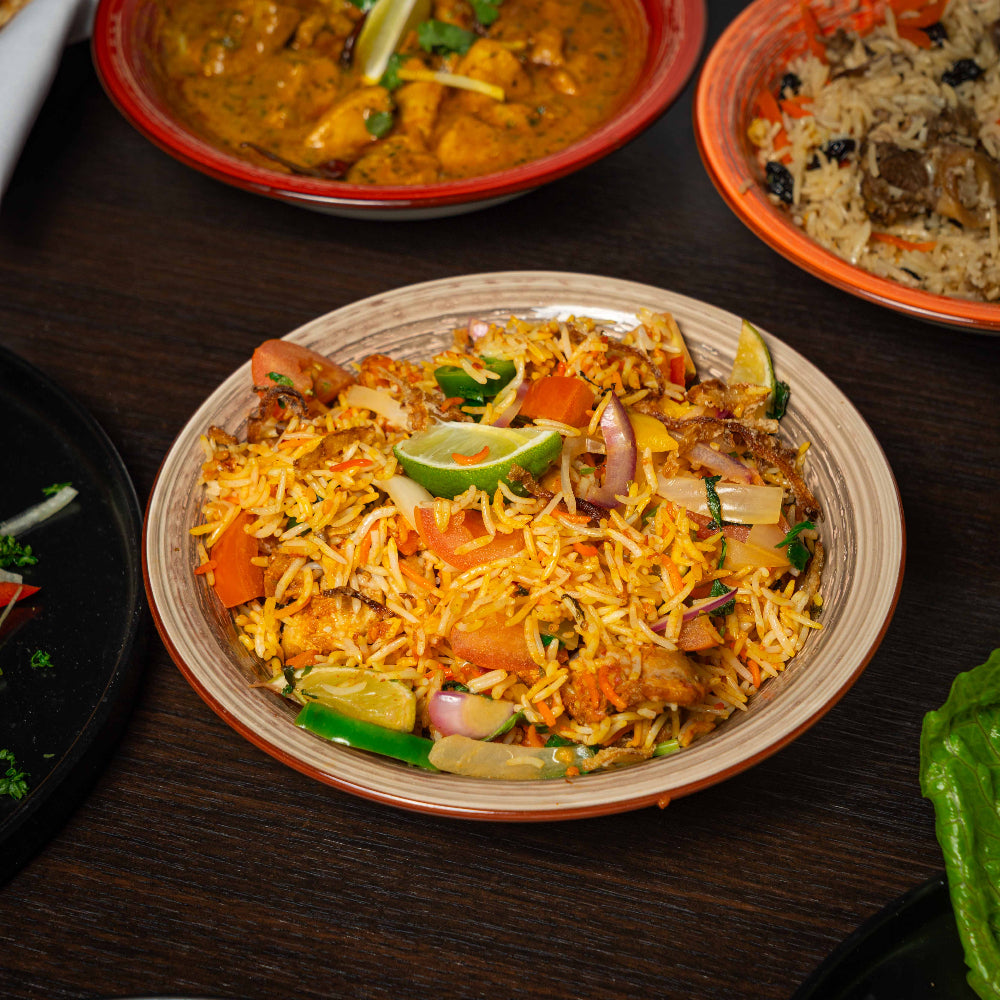 Plated dish of biryani with vegetables on a wooden table