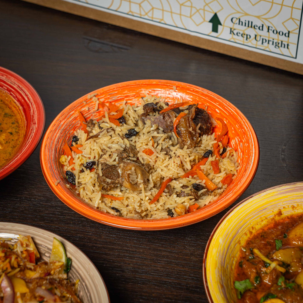 Bowl of rice with meat and vegetables on a wooden table