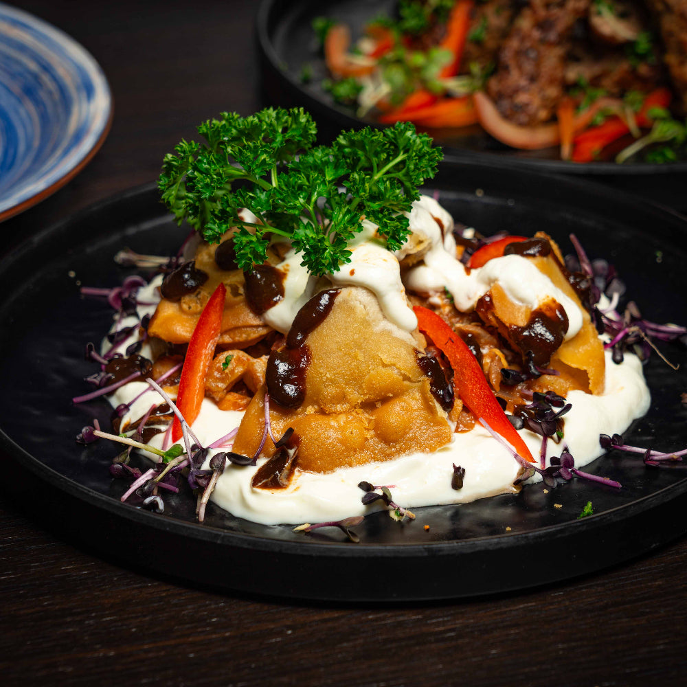 Plated dish with chicken, vegetables, and sauce on a dark surface