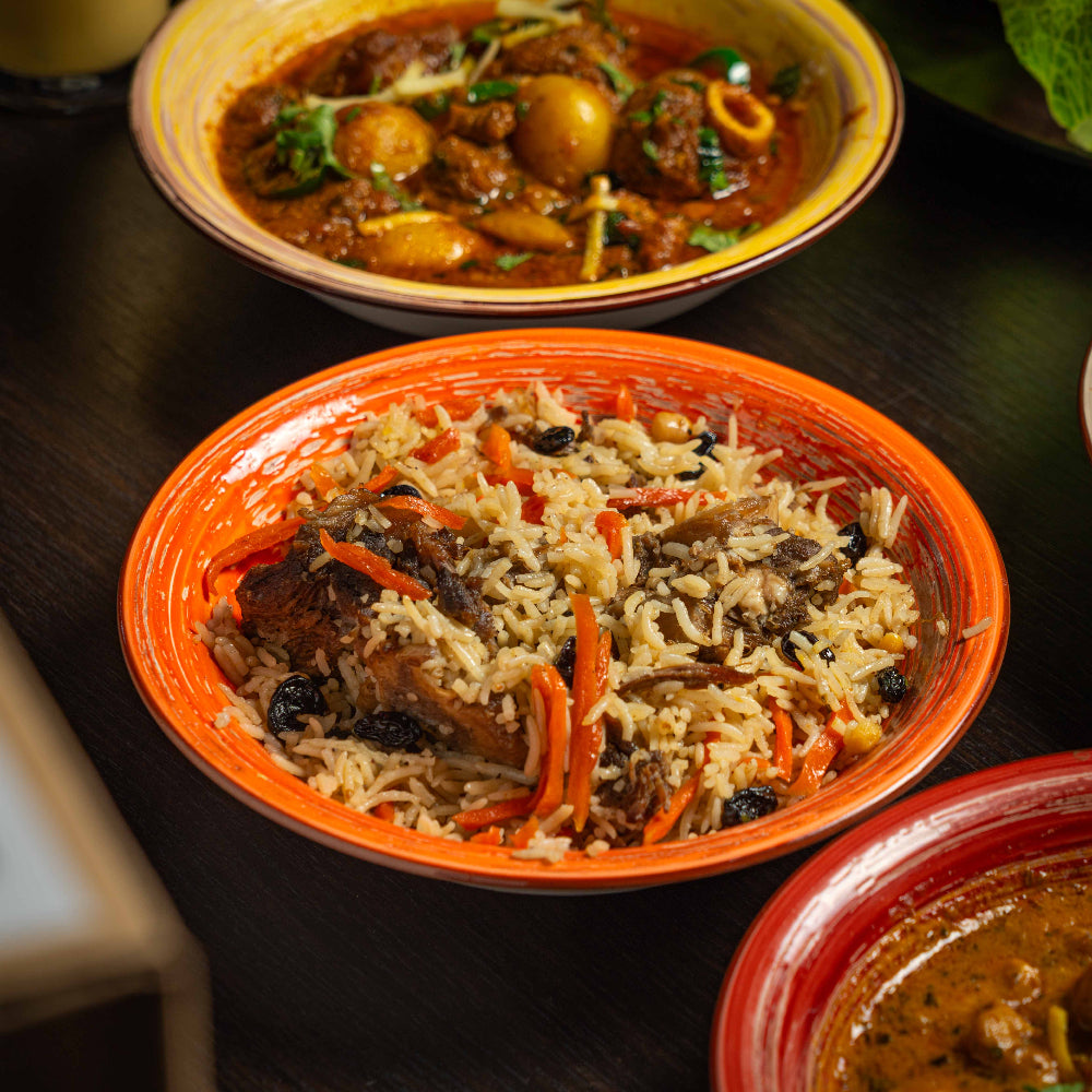 Three bowls of different curry dishes on a dark surface from midpoint aagrah